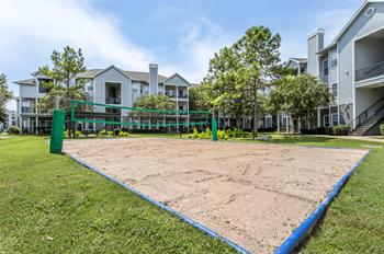 A sand volleyball court is surrounded by apartment buildings